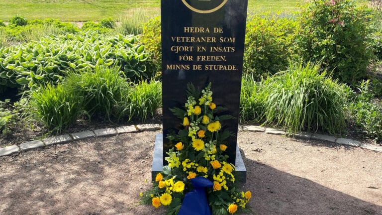 Blomsterarrangemang ligger vid foten av minnesstenen.