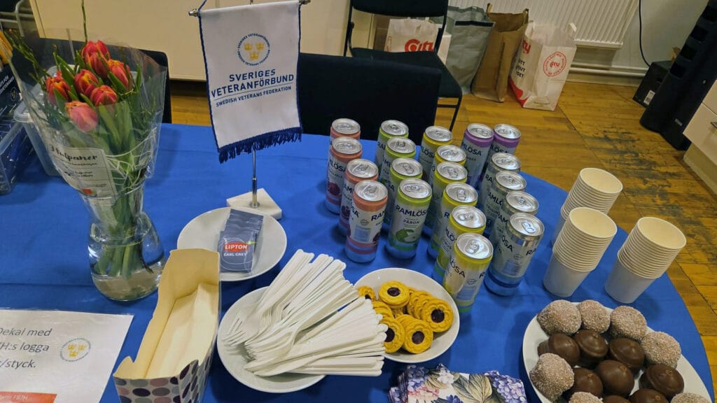 Ett bord med blå duk, kakor och burkar med Ramlösa.